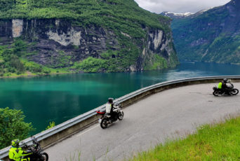 Norwegen-Motorradfahrer-in-der-Kurve-am-Fjord